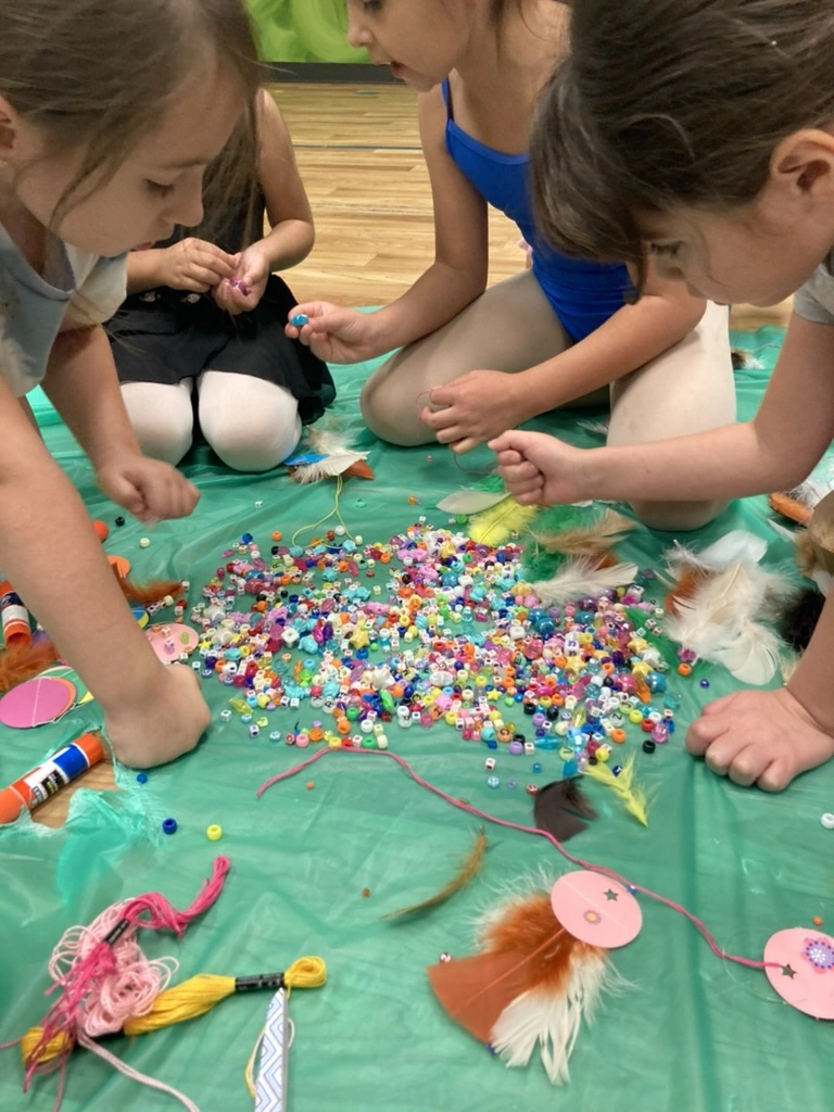 Campers making beaded feather crafts together