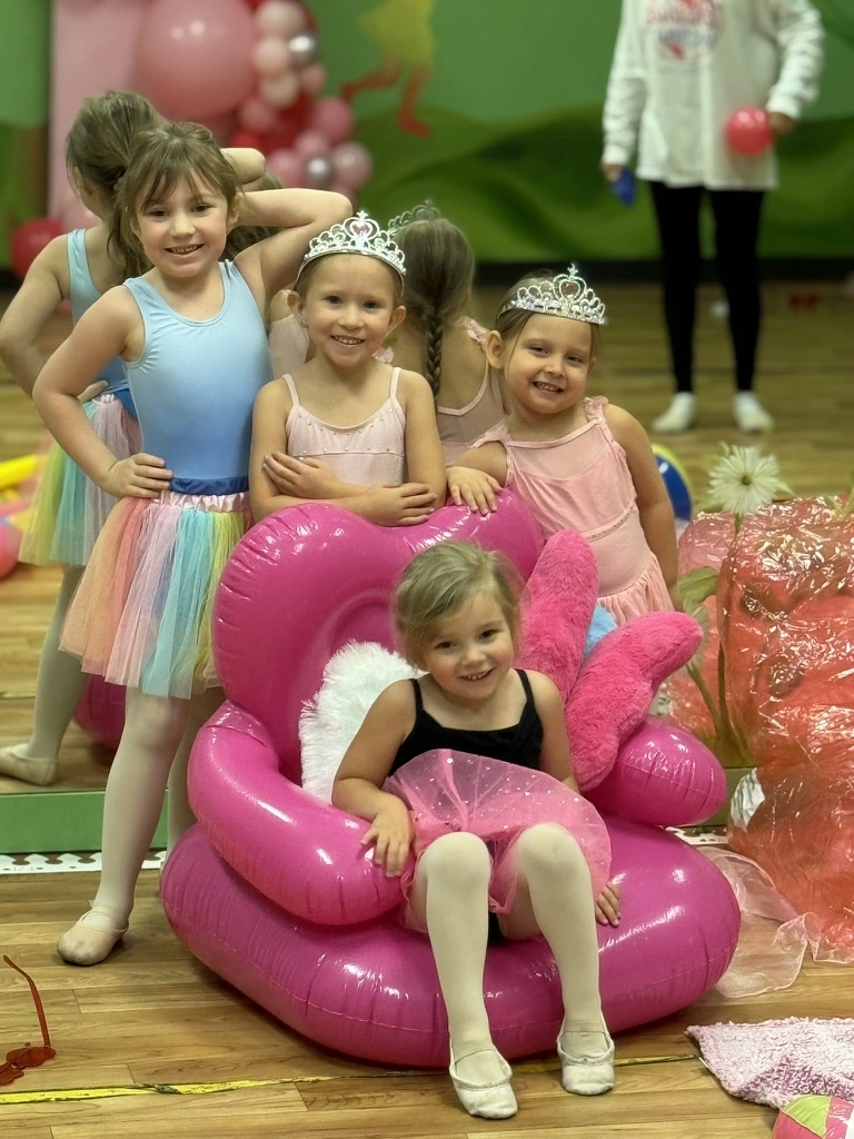 Smiling summer campers in tiaras around a pink throne