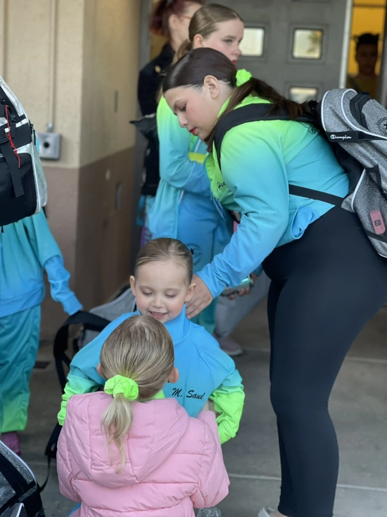 An older company dancer helping a younger teammate