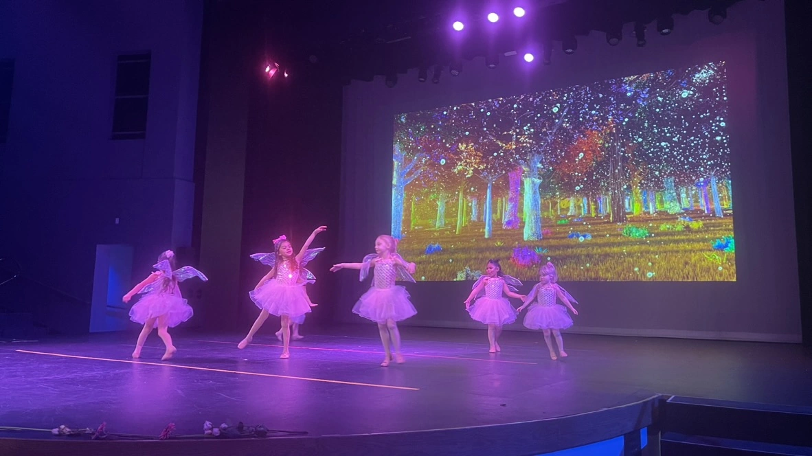 Young company dancers dancing as fairies in front of a sparkling forest