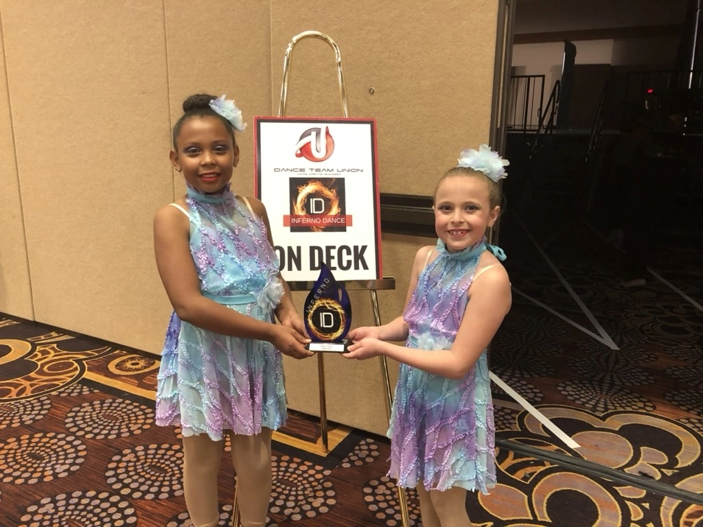 Two company dancers in matching lyrical costumes with their Inferno Dance award