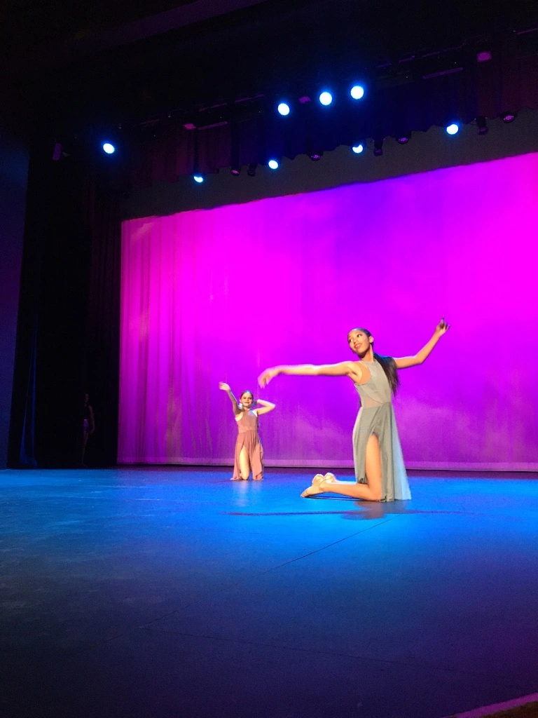 Two company dancers performing a lyrical piece on a magenta-lit stage