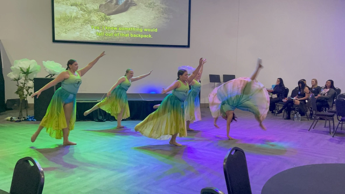 Company dancers in ombre dresses with a cartwheel during a community performance