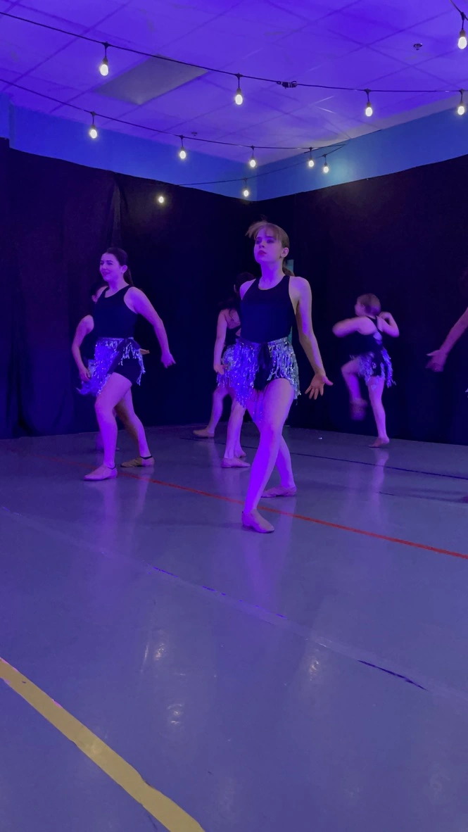 Company dancers performing a sequin jazz number in a studio showcase