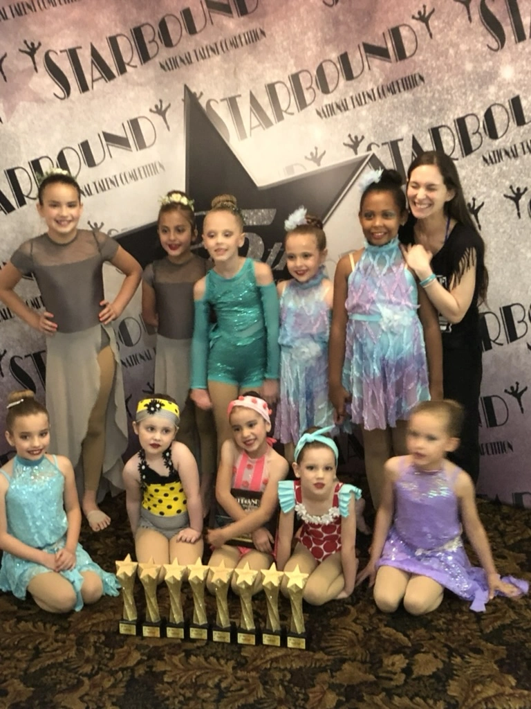 Young Movement Dance Company dancers with a row of gold trophies at Starbound