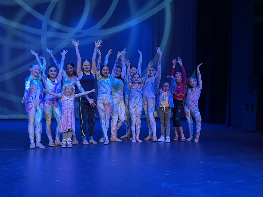 The Movement Dance Company cast in tie-dye costumes taking a bow on stage