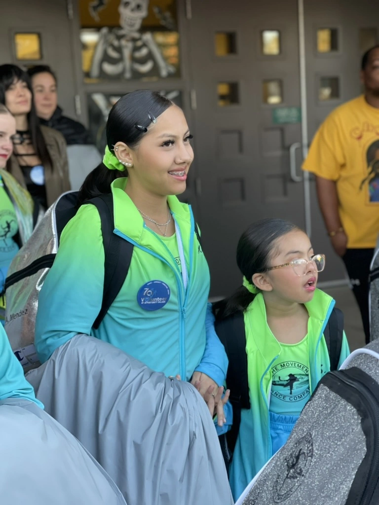 Company dancers in team jackets at a community volunteer event