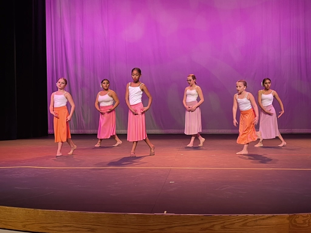Company dancers in yellow tops kicking in a contemporary number