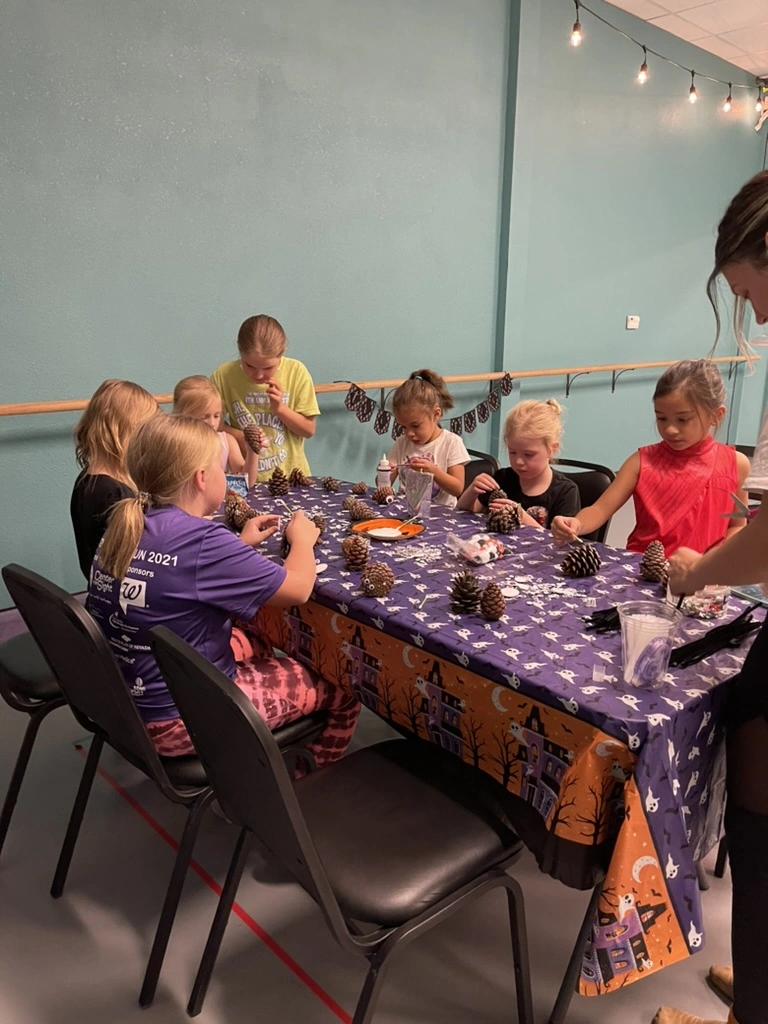 Kids making pinecone crafts at a Movement Halloween party