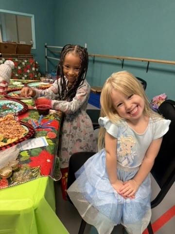 Two smiling girls at a Movement holiday party table