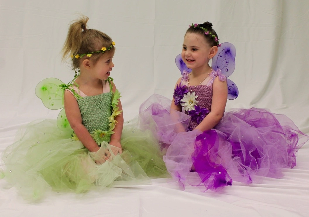 Two tiny fairies in green and purple tutus giggling together