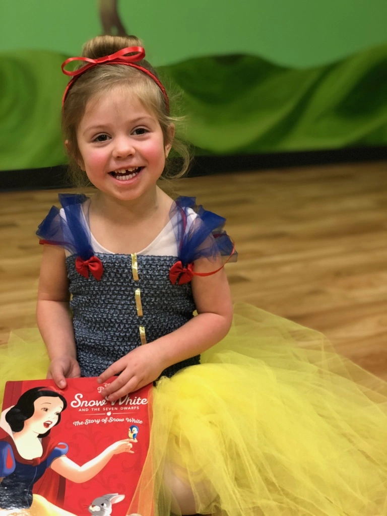 A smiling little Snow White holding her storybook