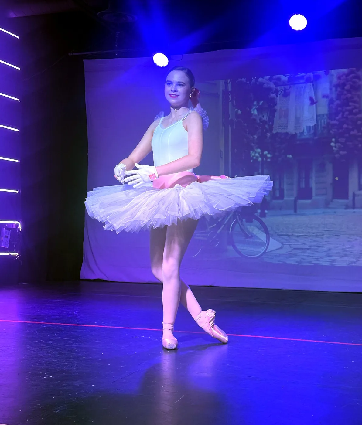 A ballerina dancing a solo in a white tutu on the Ovation Theatre stage