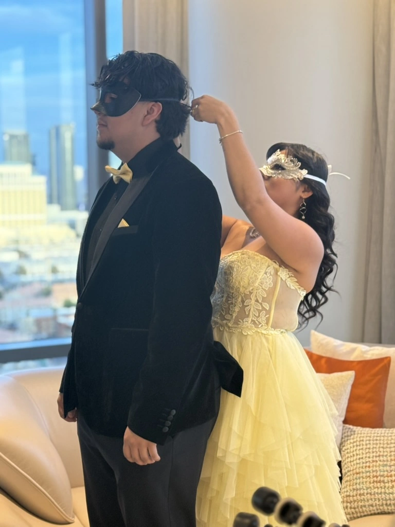 A couple putting on masquerade masks before their formal dance