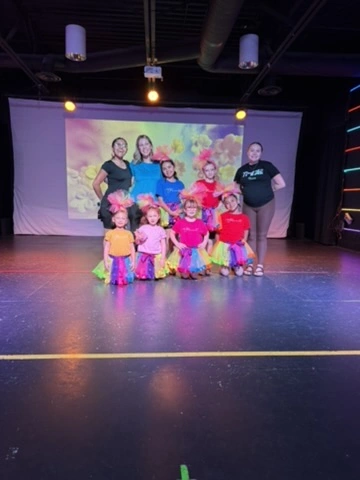 The Spotlight Academy cast in colorful Trolls tutus on the Ovation Theatre stage