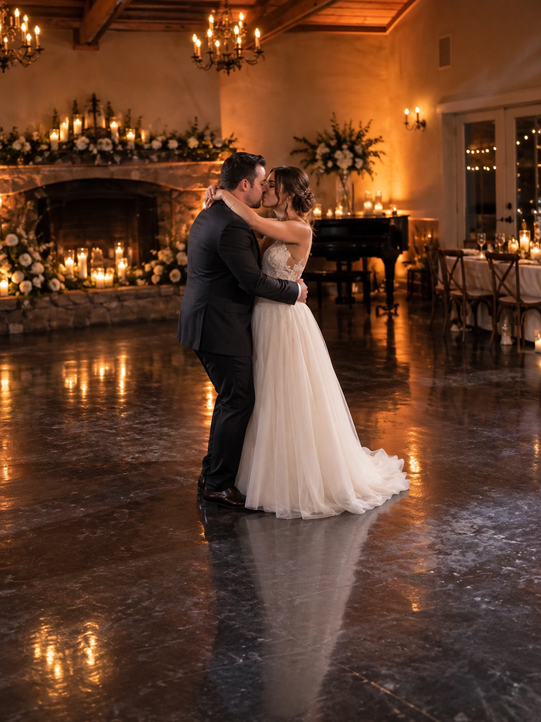 A bride and groom sharing a first dance in a candlelit ballroom